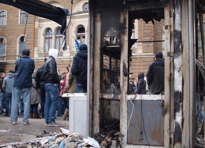 Люди стоят возле разрушенного президентского здания в Сараево, 9 февраля