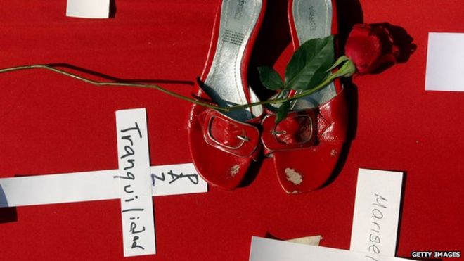 Туфли жертвы видны рядом с цветком и крестом во время мессы по случаю первой годовщины преступления в Монтеррее, Мексика, в котором погибло 52 человека 25 августа 2012 года.
