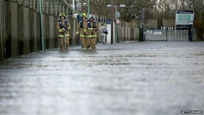 Пожарные идут по затопленной улице в Чертси