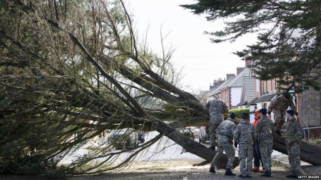 Солдаты помогают деревяному хирургу убрать упавшее дерево в Эгхеме, западный Лондон