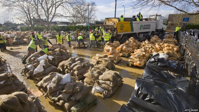 Добровольцы и благотворительные организации заполняют мешки с песком, прежде чем они распространяются в Эгхеме, к западу от Лондона.