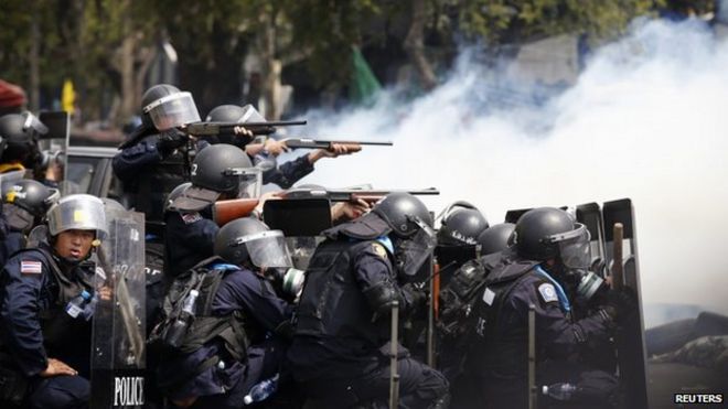 Тайские полицейские направляют свое оружие на антиправительственных демонстрантов во время столкновений возле Дома правительства в Бангкоке, 18 февраля 2014 года