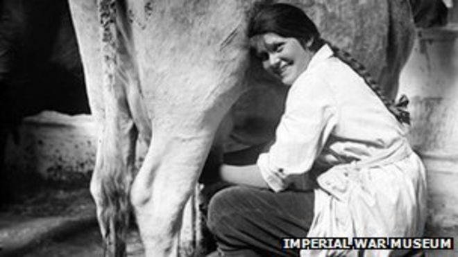 Член женской сухопутной армии доит корову.