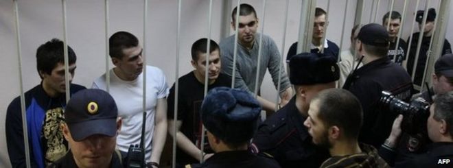 Антипутинские демонстранты, обвиняемые в подстрекательстве к массовым беспорядкам на Болотной площади, стоят в клетке обвиняемого в Замоскворецком районном суде в Москве во время суда в понедельник