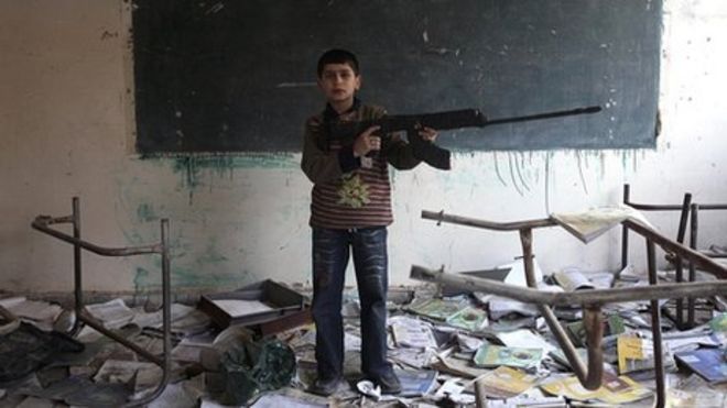 Мальчик с игрушечным пистолетом в поврежденной школе в Дейр-эз-Зоре, Сирия