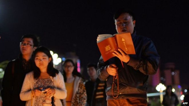 На этом снимке, сделанном 2 марта 2014 года, изображены молитвы буддистов (справа), когда скорбящие зажигают свечи на месте теракта на главном железнодорожном вокзале в Куньмине, провинция Юньнань на юго-западе Китая