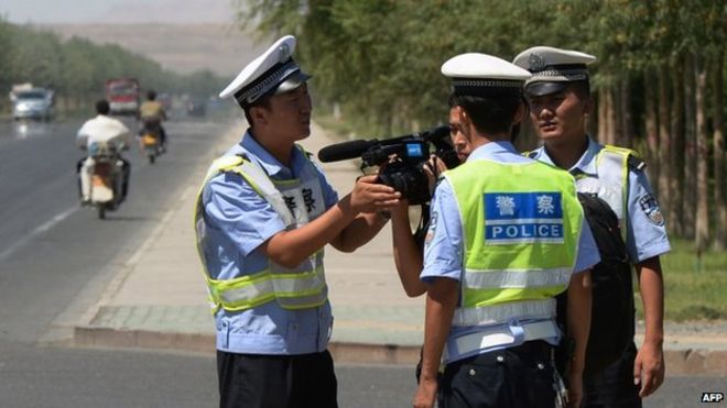Файл с фотографией китайской полиции, задерживающей журналиста на контрольно-пропускном пункте на дороге в город Лукцунь в провинции Синьцзян, 28 июня 2013 г.