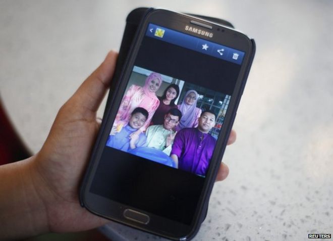 Арни Марлина, 36 лет, член семьи пассажира на борту рейса MH370, показывает семейную фотографию на своем мобильном телефоне в отеле в Путраджайе, Малайзия, 9 марта