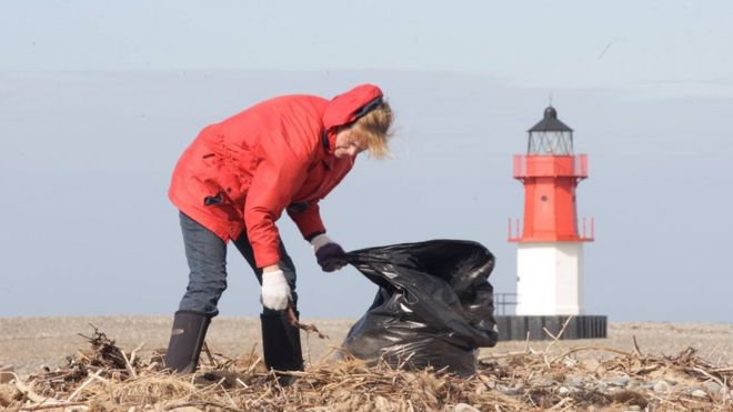 Женщина собирает мусор на пляже