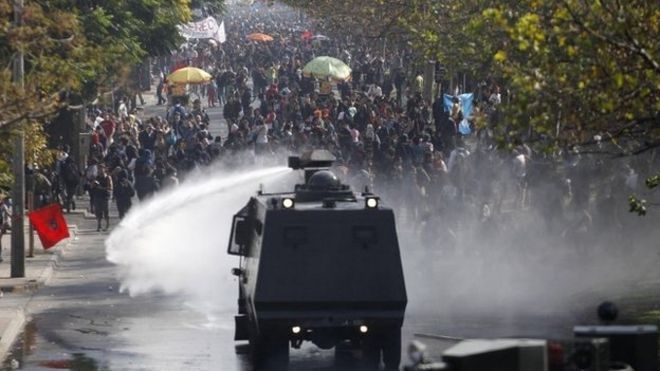 Водяная пушка полиции выпускает струю воды на протестующих студентов в Чили, апрель 2013 года