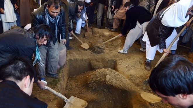 Друзья и семья покрывают могилу одного из детей Сардара почвой во время похорон. Сотни доброжелателей оказались под проливным дождем