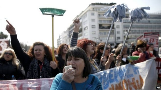 Протестующие уборщики, уволенные министерством финансов, провели марш с ведрами и швабрами во время митинга у парламента Греции в центре Афин 12 марта 2014 года.