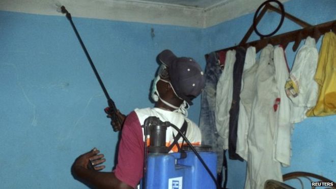 Медицинский работник распыляет дезинфицирующее средство в доме, принадлежащем человеку, подозреваемому в контакте с вирусом Эбола, в Масенте, Гвинея - 26 марта 2014 года