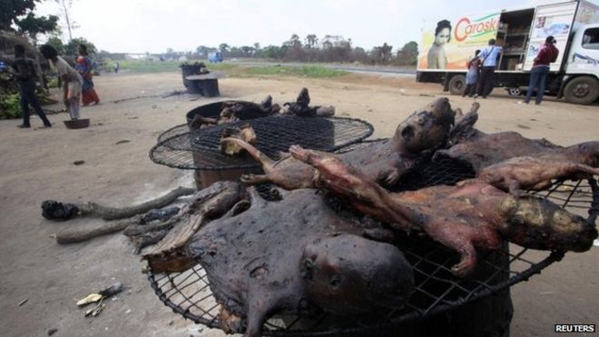 Люди идут возле сушеного мяса диких животных возле дороги на шоссе Ямусукро в Кот-д'Ивуаре - 29 марта 2014 года