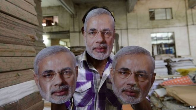 Индийский рабочий позирует с масками с лицом кандидата в премьер-министры БДП Нарендры Моди в типографии возле Ахмедабада 31 марта 2014 года