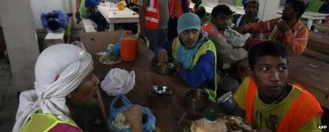 Рабочие-мигранты во время обеденного перерыва работают 3 октября 2013 года в Дохе в Катаре