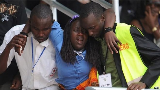 7 апреля 2012 года на стадионе «Амахоро» в Кигали женщине помогают во время церемонии, посвященной 20-й годовщине геноцида в Руанде.