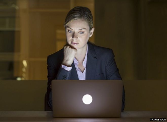 Женщина смотрит на компьютер поздно ночью