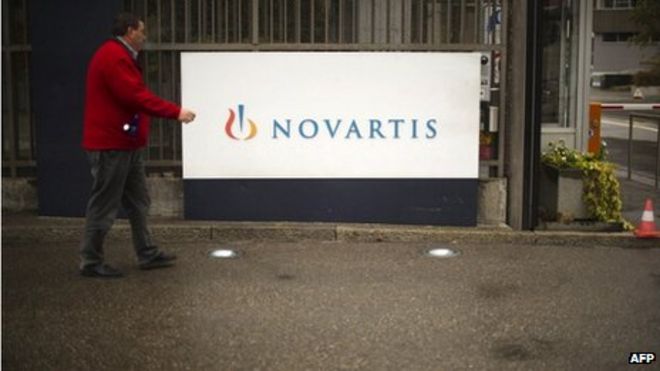 Человек, идущий перед логотипом Novartis