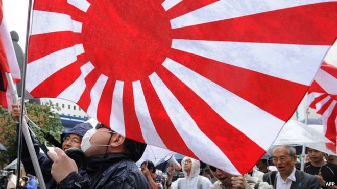 На этом снимке, сделанном 23 сентября 2012 года, изображены члены правого отряда, поднимающего флаг восходящего солнца Японии во время митинга в Токио