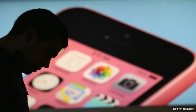 Человек вырисовывается перед изображением Apple iPhone 5C