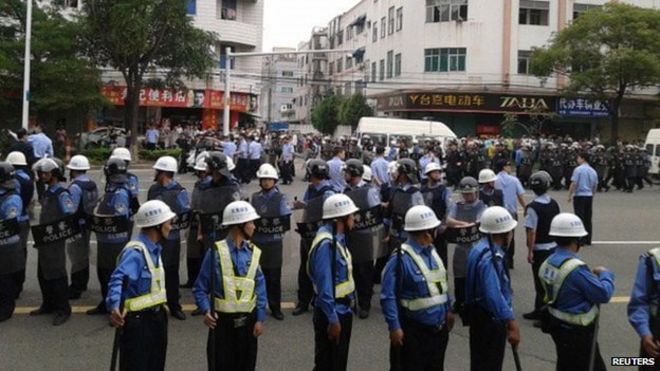 Полицейские замечены во время патрулирования, когда рабочие бастуют возле фабрики Yue Yuen в Дунгуане, провинция Гуандун, 15 апреля 2014 года