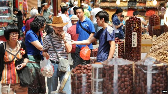 5 июля 2013 года туристы покупают различные местные продукты на городском базаре в Урумчи, район Синьцзян, на западе Китая.