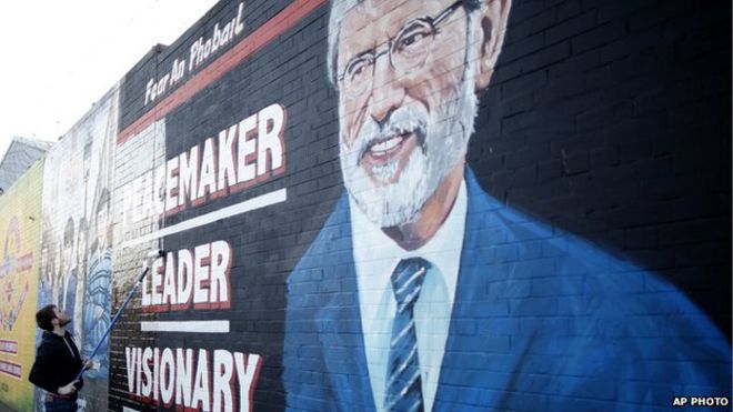 Человек рисует фреску Джерри Адамса в Западном Белфасте
