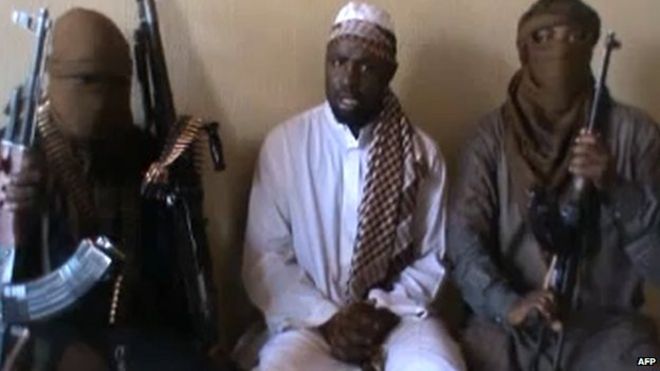 Снимок экрана, снятый из видео, выпущенного на YouTube в апреле 2012 года, на котором, видимо, изображен лидер «Боко харам» Абубакар Шекау (в центре), сидящий в окружении боевиков