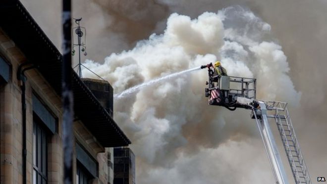 пожарный льет воду на Школу искусств Глазго