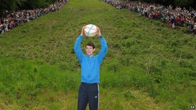 Джош Шеперд, 19 лет, из Брокворта, празднует победу в гонке по скоростному спуску среди мужчин на Cheese Rolling на Купер-Хилл