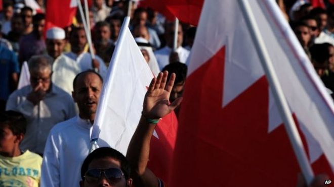 Бахрейнские антиправительственные демонстранты развевают национальные флаги во время марша в Малкии (16 мая 2014 года)