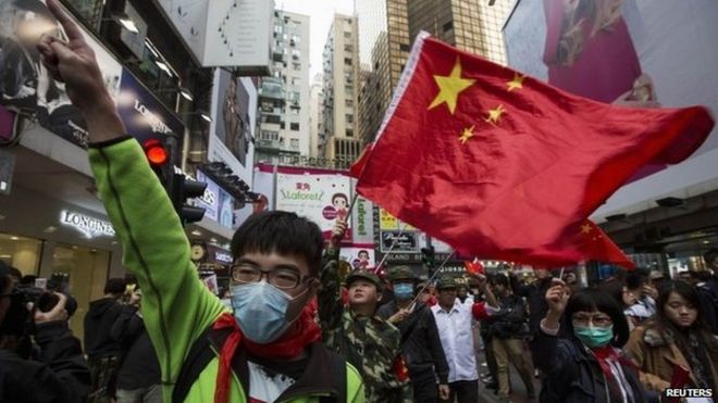Протестующие развевают китайские национальные флаги во время митинга против материка в знаменитом торговом районе Козуэй Бэй в Гонконге, 16 марта 2014 года