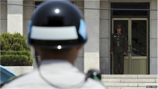 Северокорейский солдат (R) смотрит на юг с северной стороны, так как южнокорейский солдат стоит на страже в перемирие деревни Панмунжом в демилитаризованной зоне, которая разделяет две Кореи, 14 мая