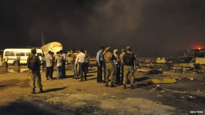 Дым вздыхает, когда сотрудники службы безопасности и сотрудники аэропорта посещают место, поврежденное в результате воскресного талибского нападения на международный аэропорт Джинна в Карачи, 9 июня 2014 года