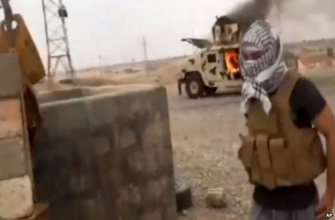 Исламистский боец ??возле горящей иракской армии Хамви в Тикрите, 12 июня