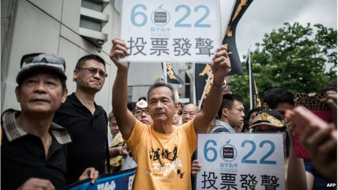 Демонстранты, поддерживающие движение Occupy Central, демонстрируют плакаты, в которых жители просят проголосовать 22 июня во время акции протеста возле представительства Пекина в Гонконге 11 июня.
