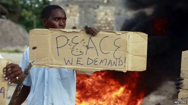 Житель держит плакат в знак протеста против недавнего нападения на прибрежный кенийский город Мпекетони 17 июня 2014 года.