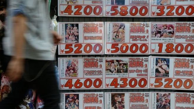 Человек проходит мимо рекламу порно анимации DVD-дисков в передней части второй части DVD магазина в Токио 4 июня [[