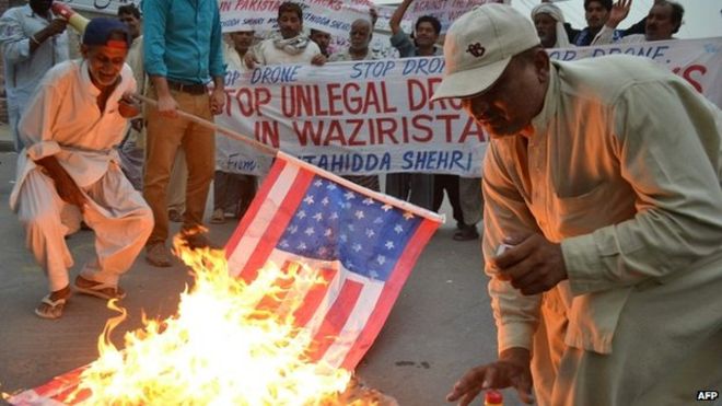 Пакистанские демонстранты сжигают американский флаг во время акции протеста против удара беспилотника США - 12 июня 2014 года