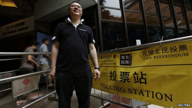 Доцент кафедры права Бенни Тай позирует возле избирательного участка в Гонконге 22 июня 2014 года