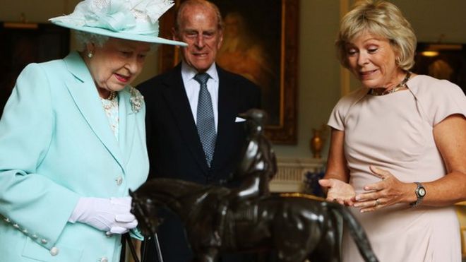 Королева и герцог Эдинбургский изучают небольшую бронзовую статую