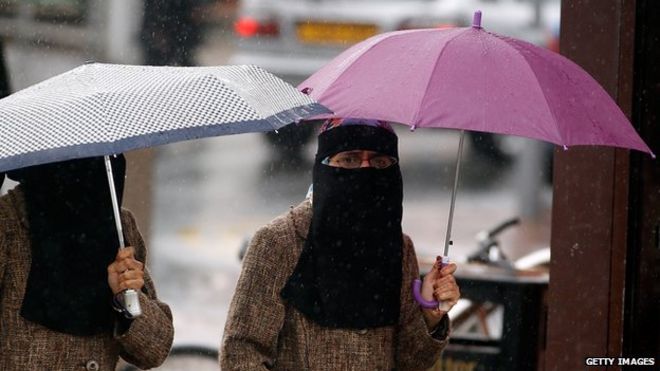 Женщины, укрывавшиеся под зонтиками, носят полное лицо Никаб на улицах Блэкберна 20 июля 2010 года.