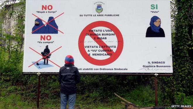 Молодой мальчик смотрит на доску 30 апреля 2012 года в Варальо, Италия, и говорит, что в этом городе запрещены бурка, никаб и буркини ..