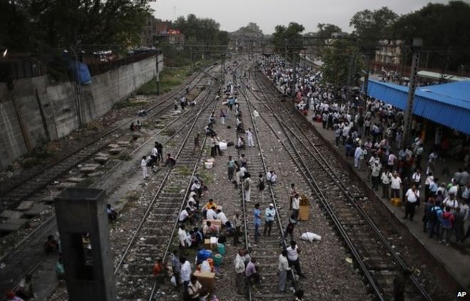 Индийские люди пересекают железнодорожный путь в Дели, Индия.