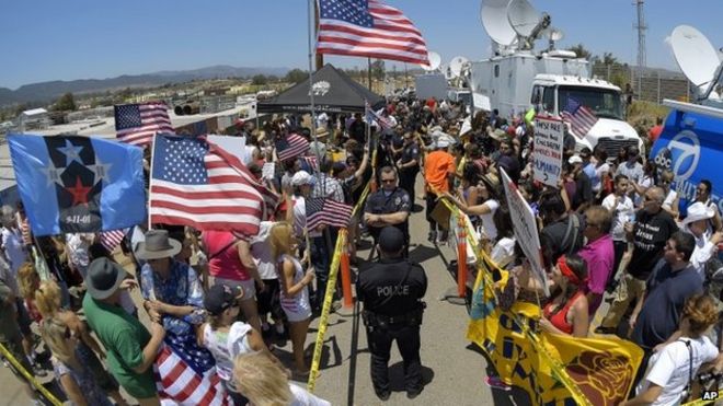 Демонстранты от противоборствующих сторон противостоят друг другу во время разлуки с полицейскими Мурриеты возле станции пограничного патрулирования США в Мурриете, штат Калифорния 4 июля 2014 года