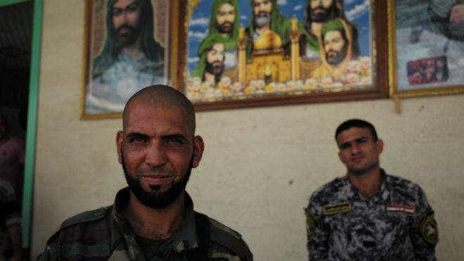 Два члена Асаиба Ахл аль-Хакка стоят возле своей штаб-квартиры к северу от Багдада - июль 2014 года