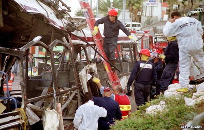 Чрезвычайный и израильский службы безопасности осматривают автобус, разрушенный в результате взрыва бомбы смертником в Хайфе 2 декабря 2001 года