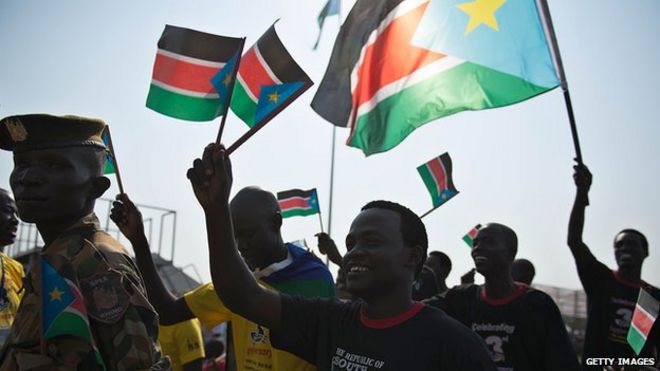 Люди размахивают флагами Южного Судана