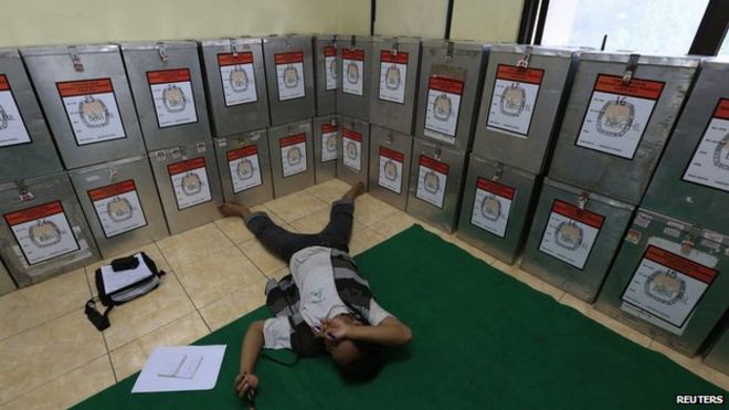 Мужчина отдыхает возле урн для голосования в Бендунган Хилир в Джакарте, на этом снимке, сделанном 10 июля 2014 года